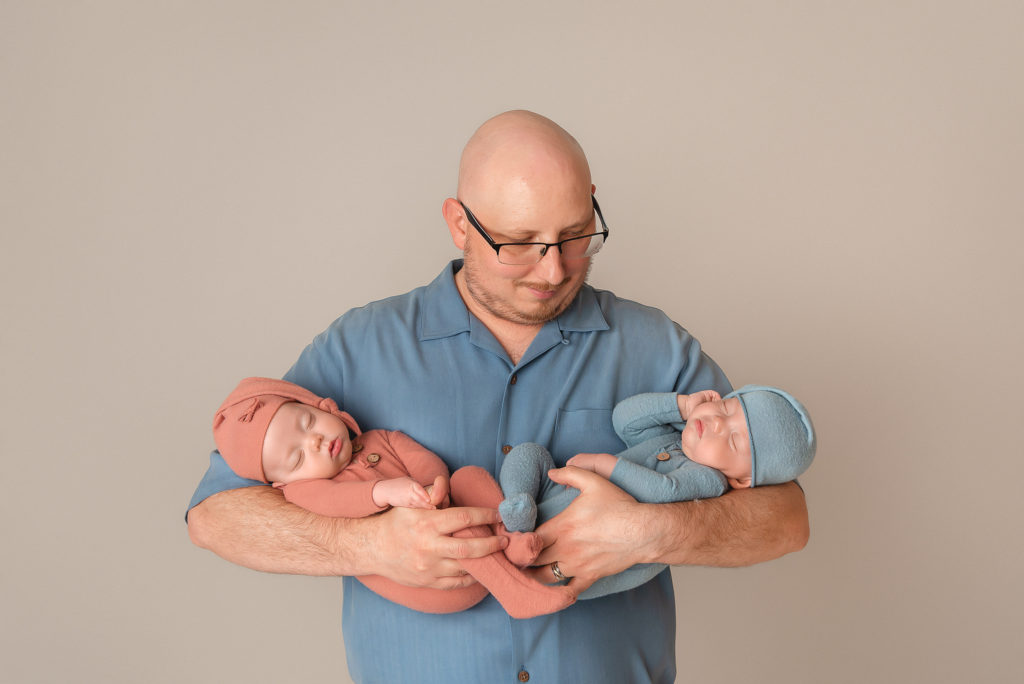 dad looks down at five month old babies during Las Vegas Studio newborn portraits